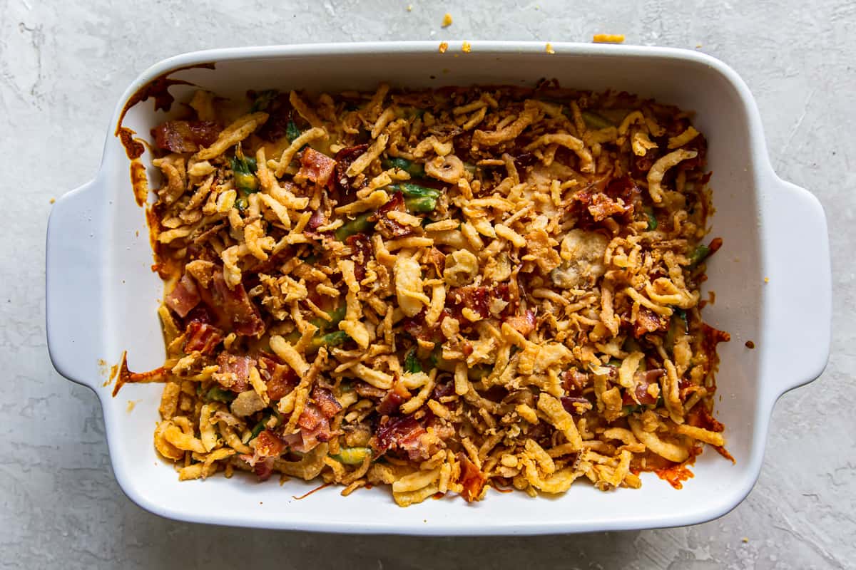 green bean casserole with cheese and bacon in a baking dish.