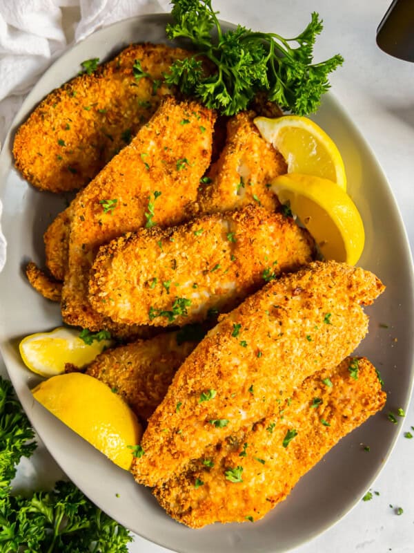 overhead image of breaded tilapia filets on a platter with lemon slices