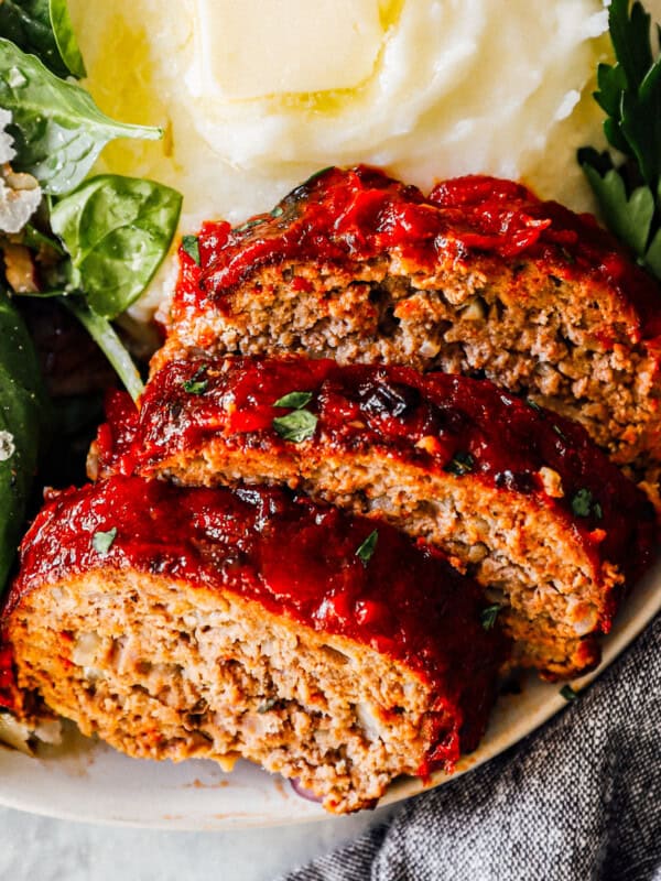 slices of air fryer meatloaf on plate with mashed potatoes and salad