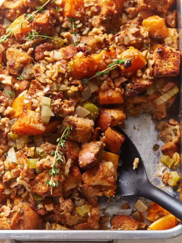 partial view of butternut squash stuffing in a baking pan with a black serving spoon.