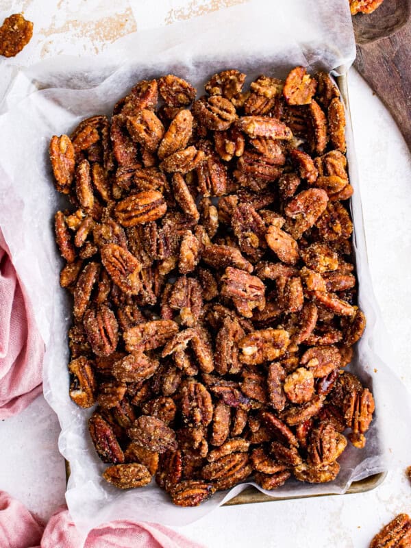 overhead image of candied pecans on a baking sheet lined with parchment paper