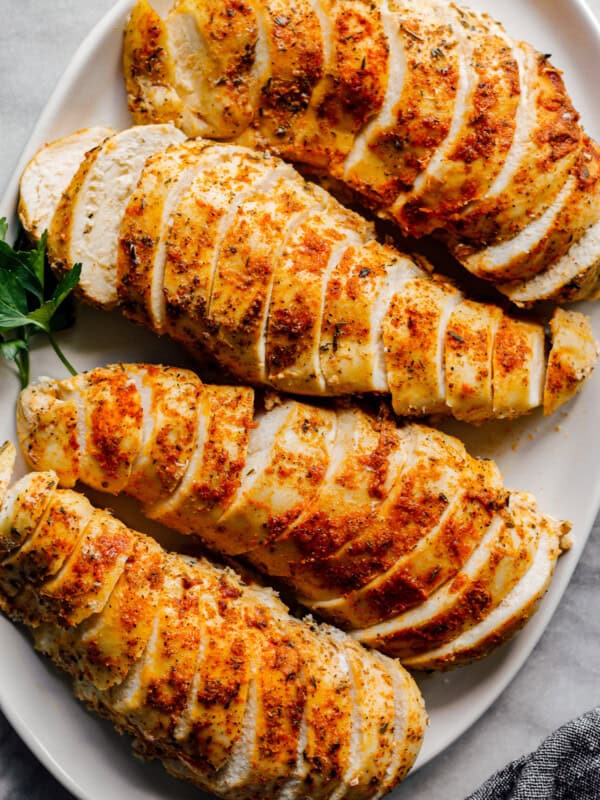 overhead sliced crockpot chicken breasts with spice rub on white plate