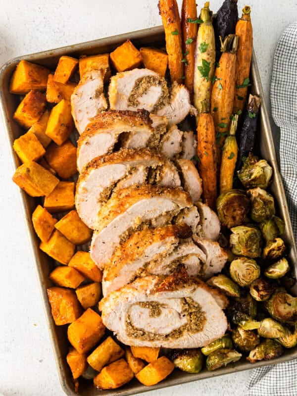 roasted sweet potatoes, carrots, and Brussels sprouts and sliced turkey roulade on a sheet pan