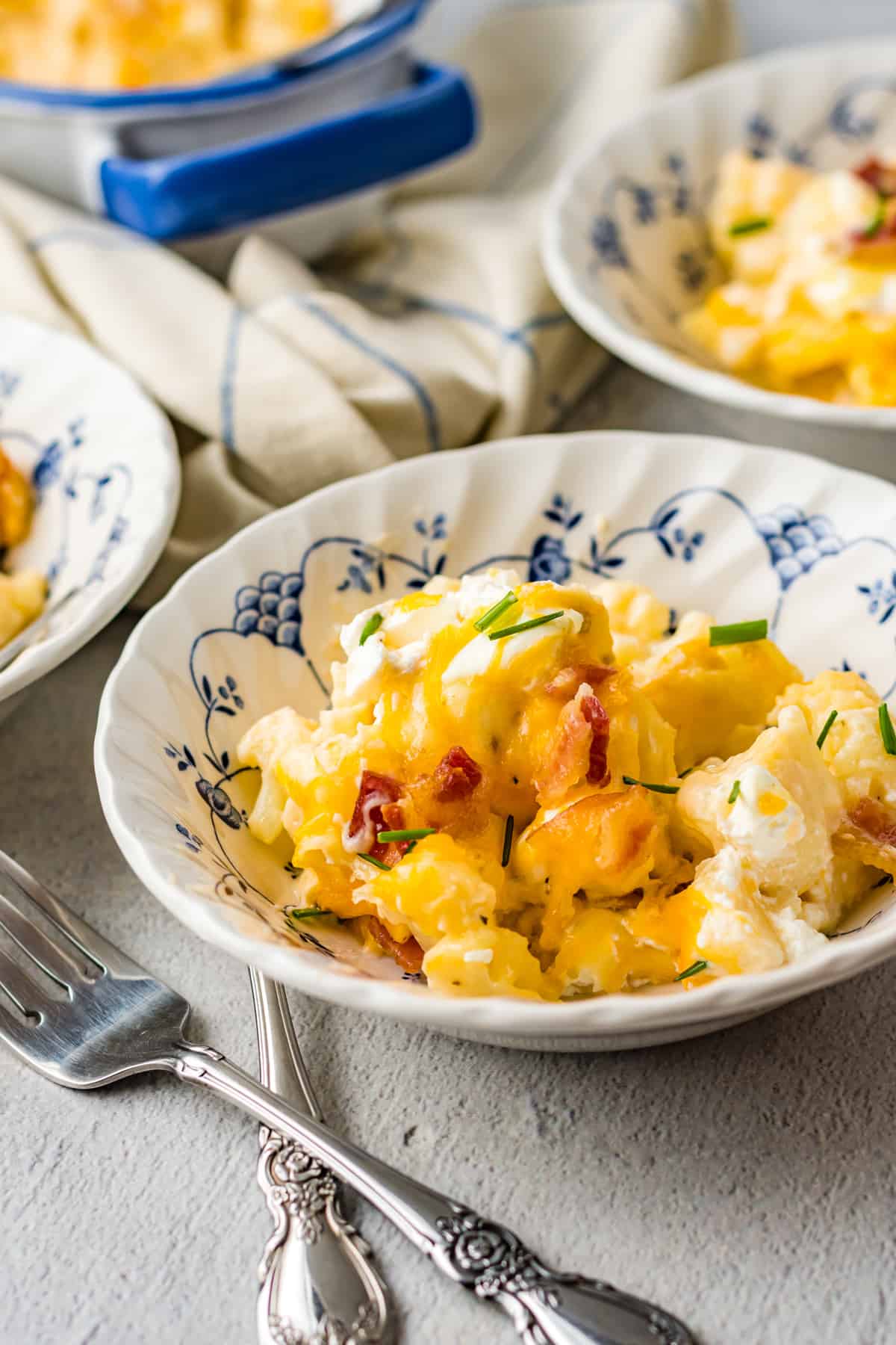 A serving of loaded cauliflower casserole in a decorative white bowl with a fork.