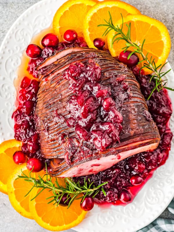 overhead image of cranberry glazed ham on a white serving platter