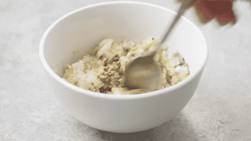 mixing spice rub with onion in a white bowl.