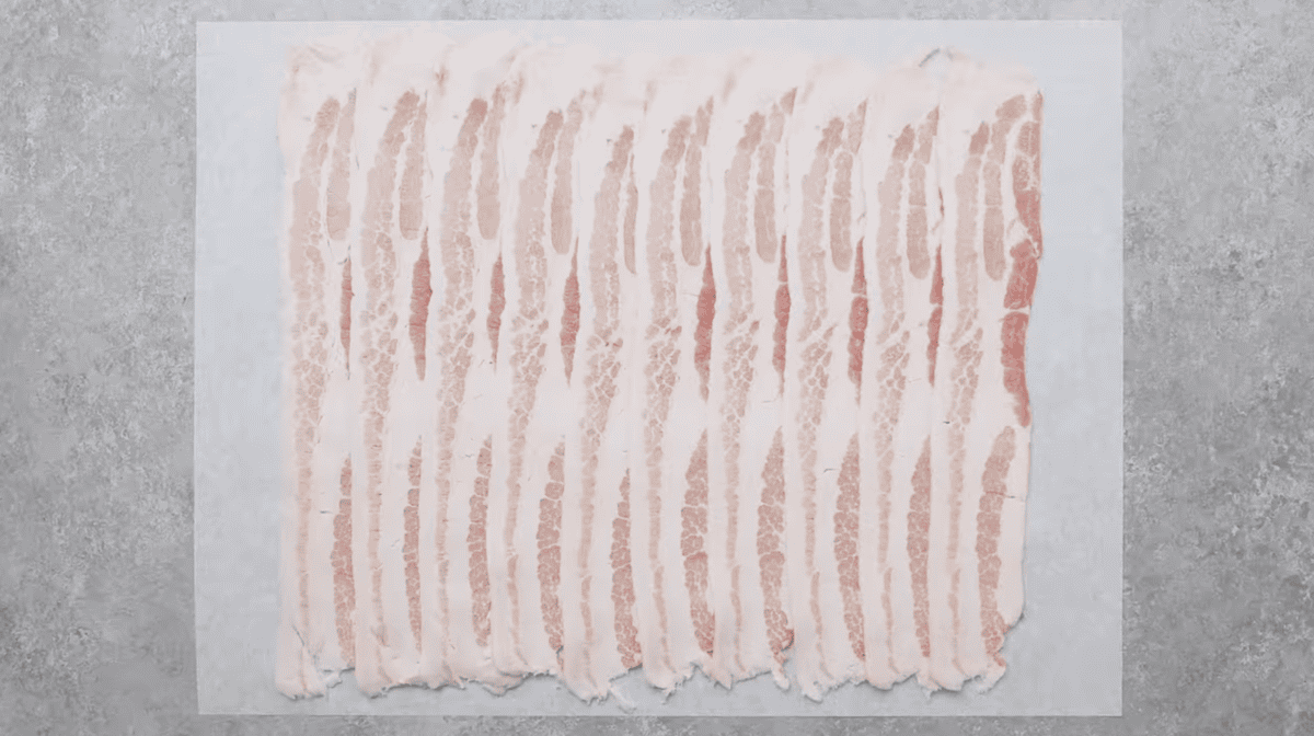 overlapping slices of bacon on parchment paper.