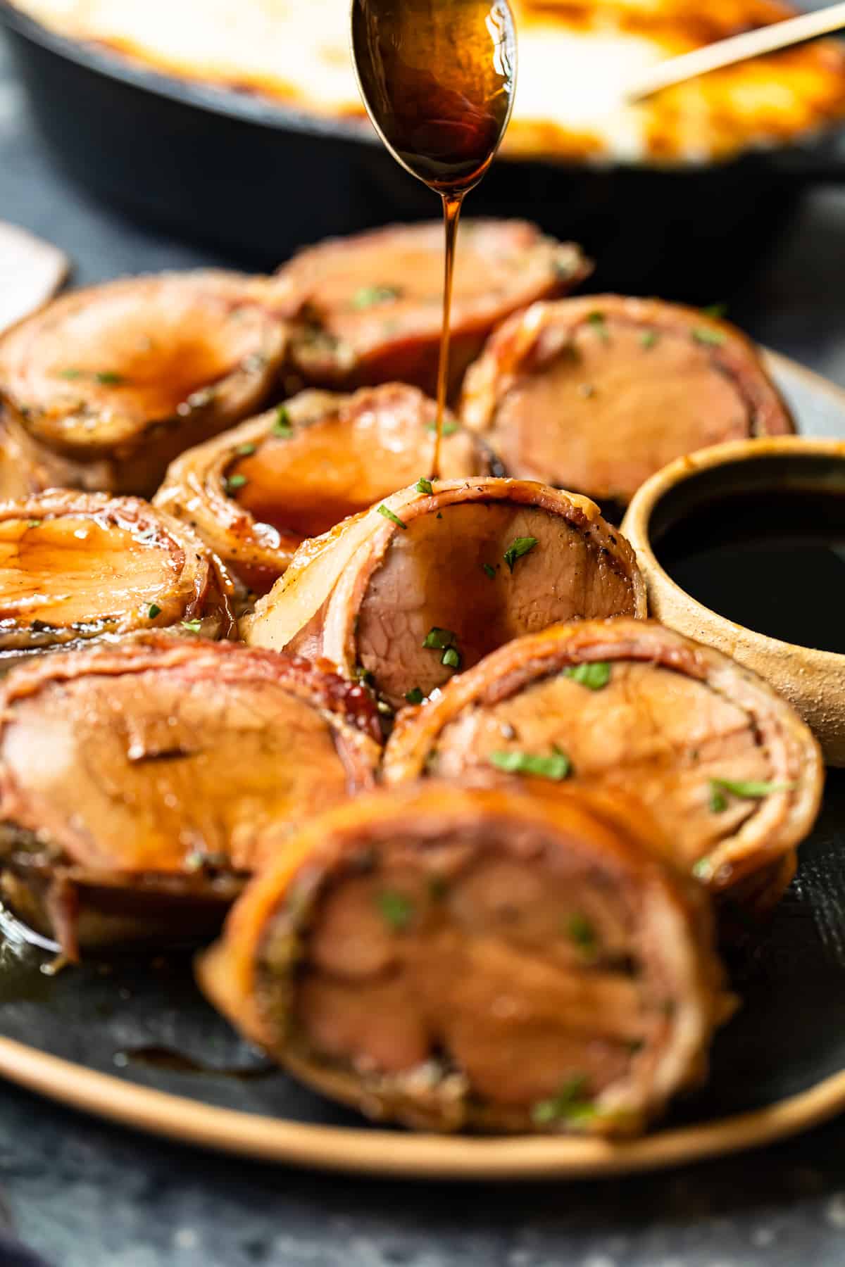 slices of bacon wrapped pork tenderloin on a serving plate