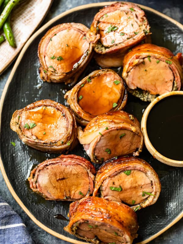 slices of bacon wrapped pork tenderloin on a serving plate