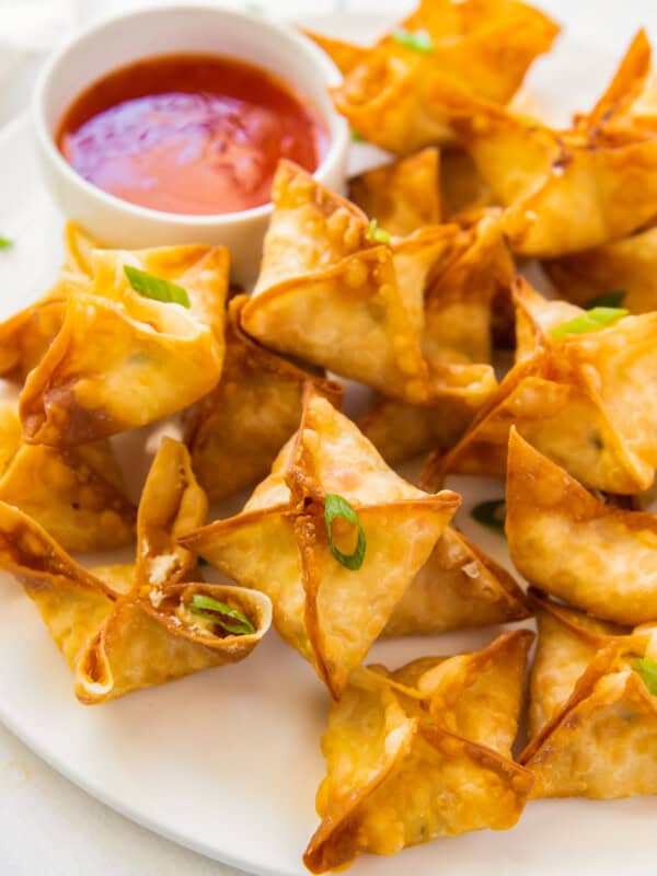 crab rangoon on white platter with sweet and sour sauce