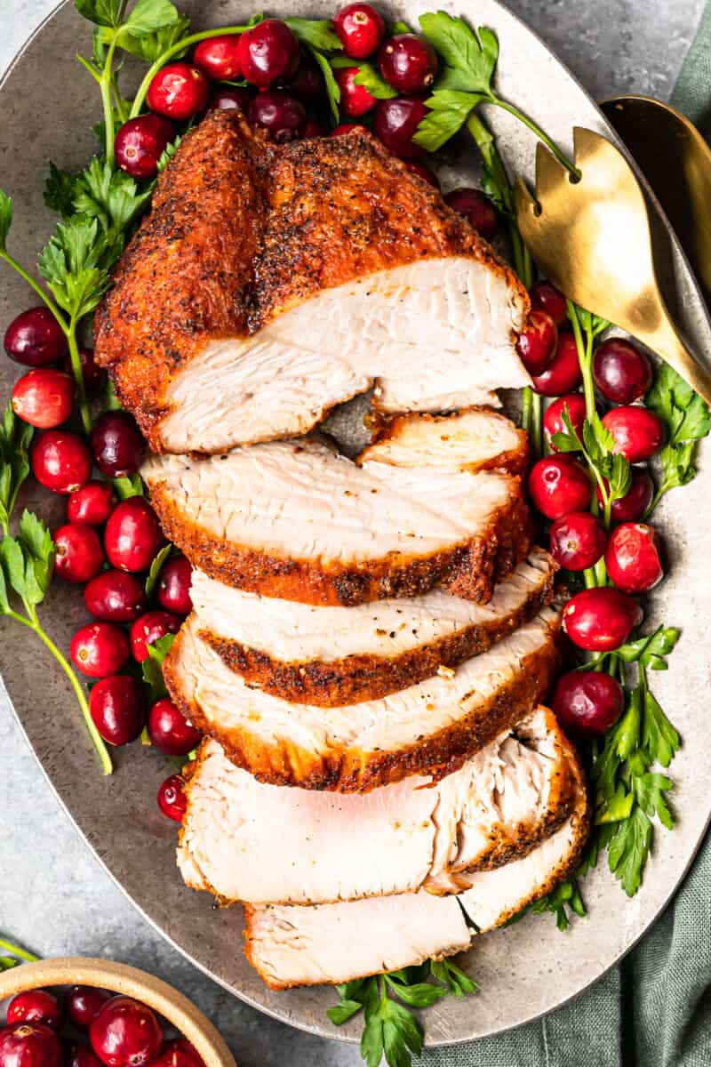 slices of deep fried turkey on a serving platter with cranberry and herb garnishes