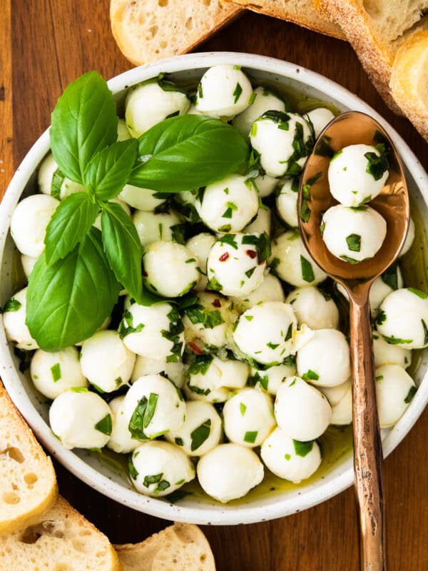 herb marinated mozzarella in white bowl with spoon