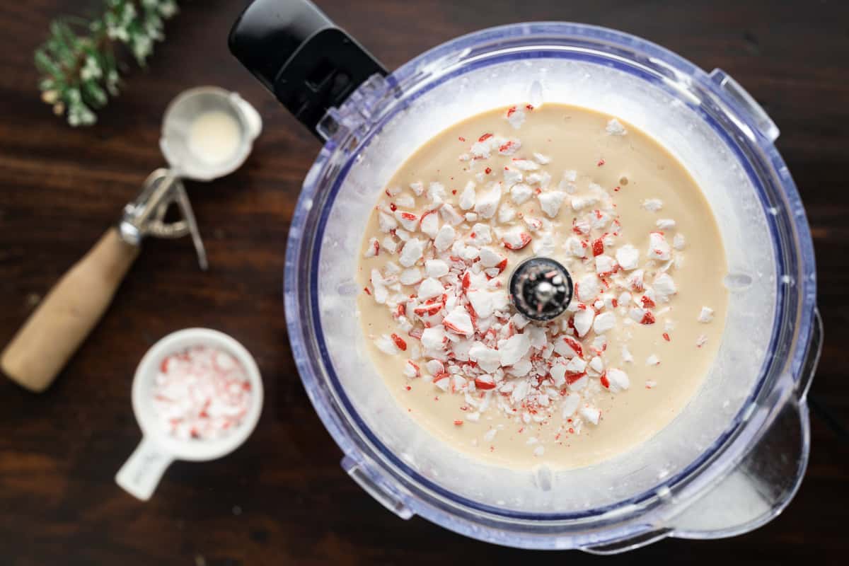 Ice cream mixture in a blender, topped with crushed peppermints.