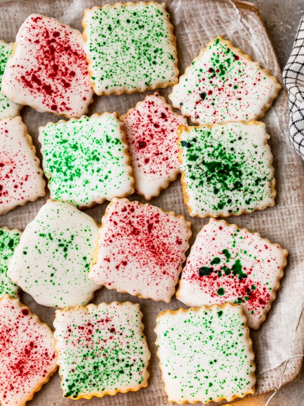 square sugar cookies topped with white icing and green and red splatter decoration