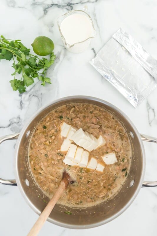 white chili in a stock pot, with cubes of cream cheese added in