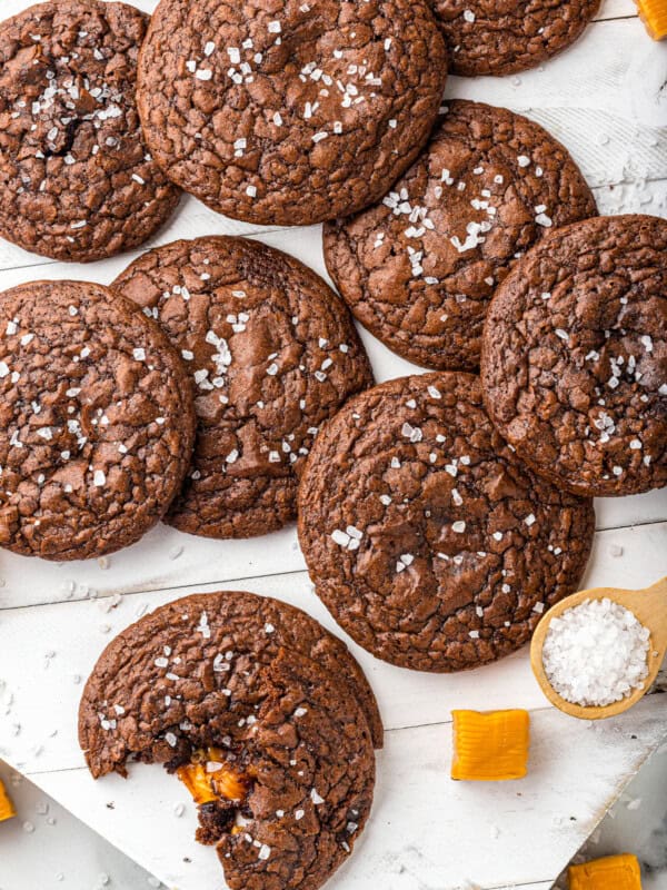 overhead image of chocolate cookies topped with sea salt with a bite taken from one cookie showing the caramel center