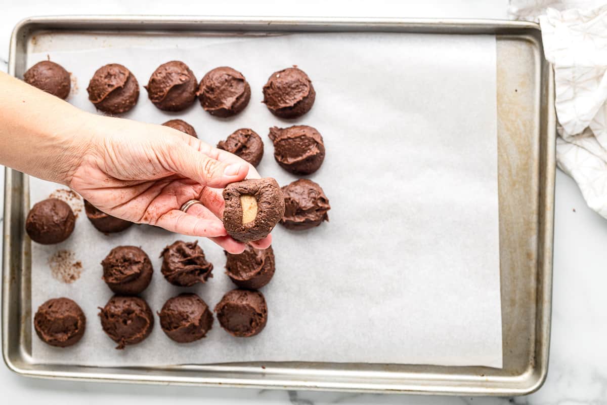 hand with a scoop of brownie cookie dough with a caramel stuffed inside covering the caramel.