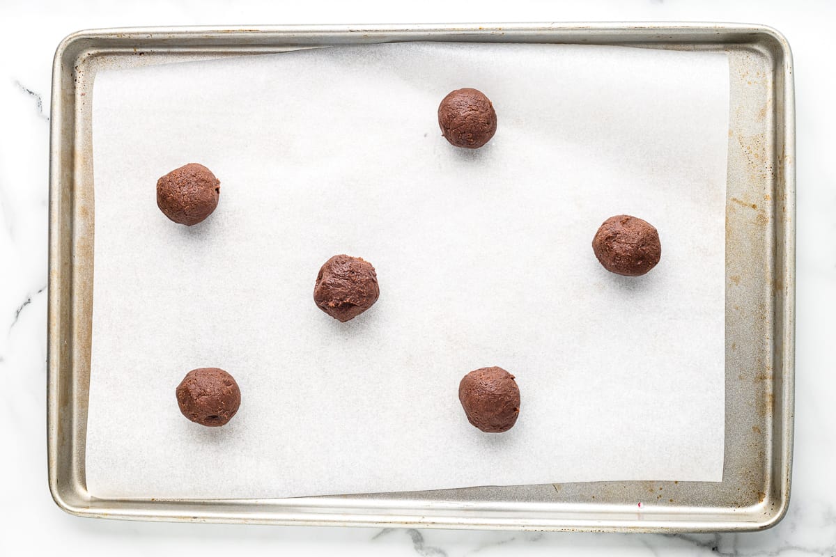 brownie cookie dough balls on a parchment paper lined baking sheet.