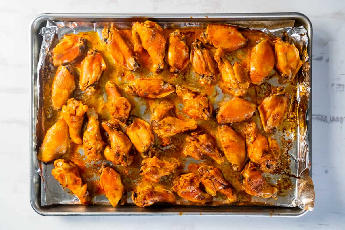 A baking tray filled with buffalo wings, after broiling.