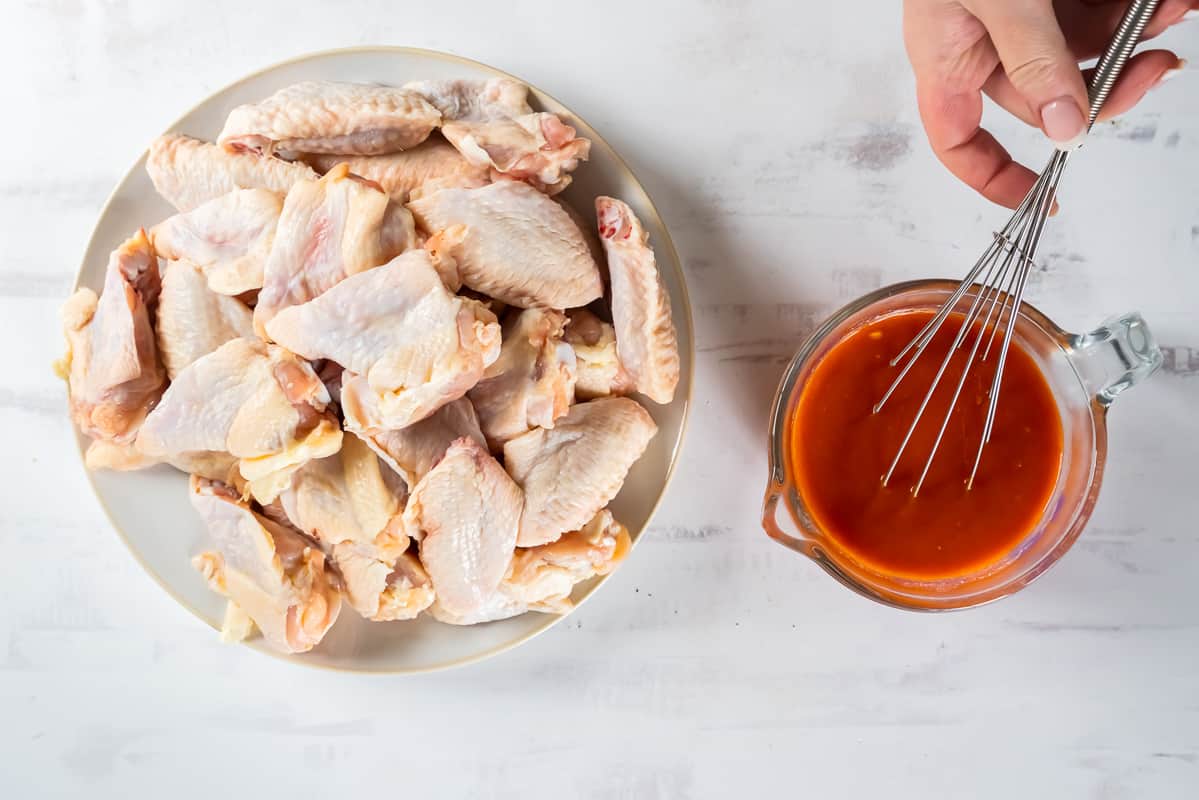 Mixing buffalo sauce ingredients, next to a plate of chicken wings.