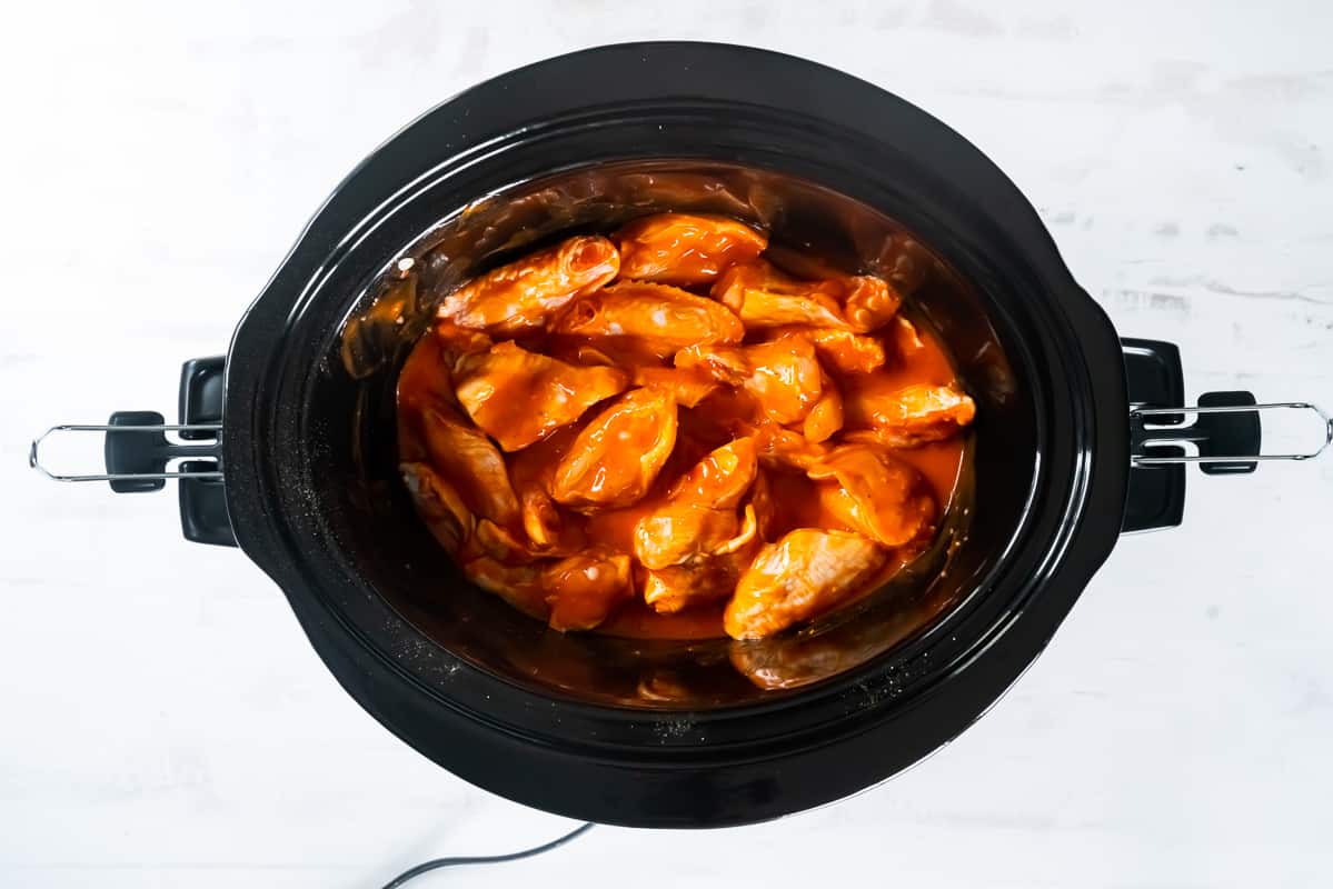 Chicken wings cooking in a slow cooker.