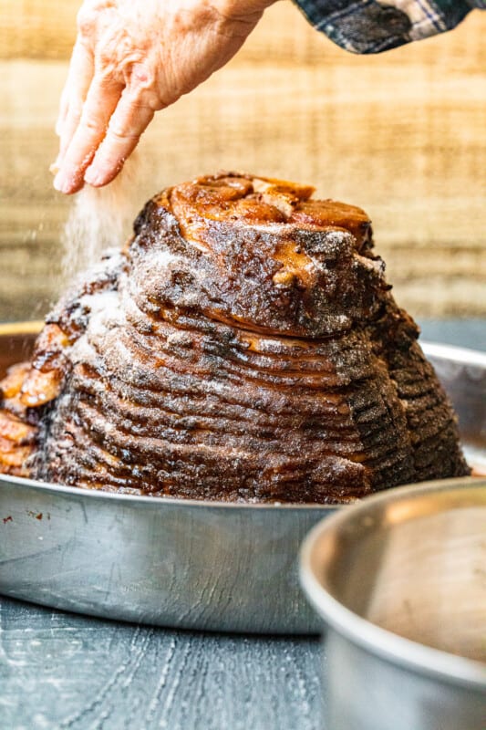 hand adding dry rub to honey baked ham