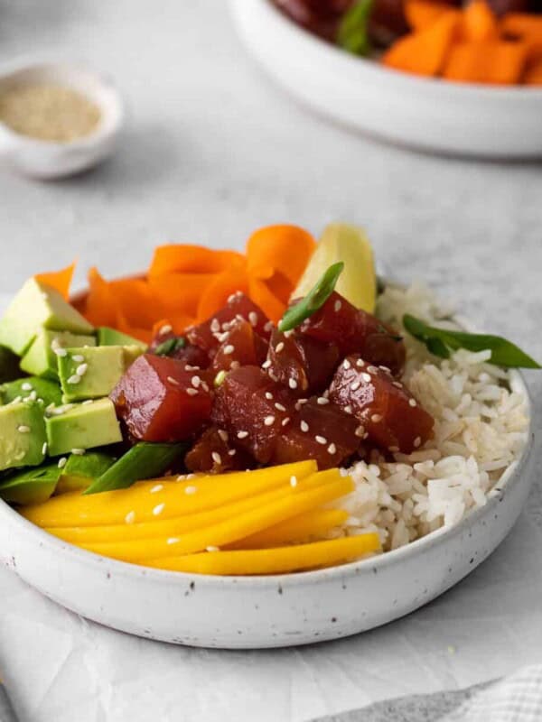 tuna poke bowl in a white bowl with chopsticks.