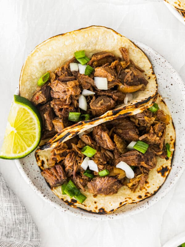 overhead image of 2 beef carnitas tacos on a white plate