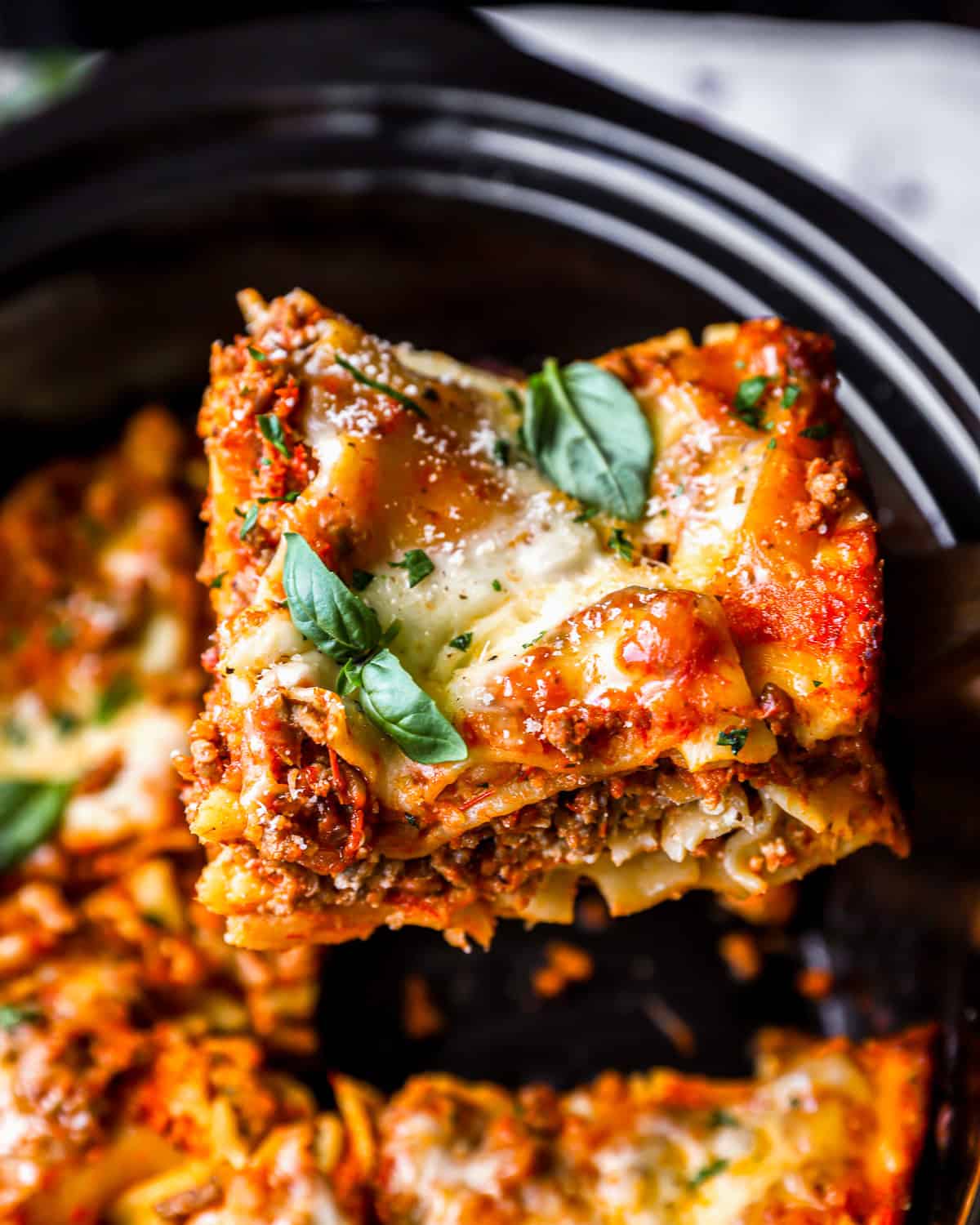 lifting a slice of lasagna from a crockpot.