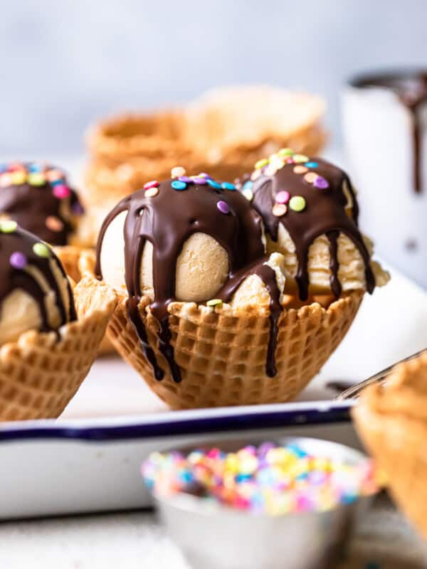 scoops of ice cream in waffle cone bowls topped with chocolate magic shell and sprinkles