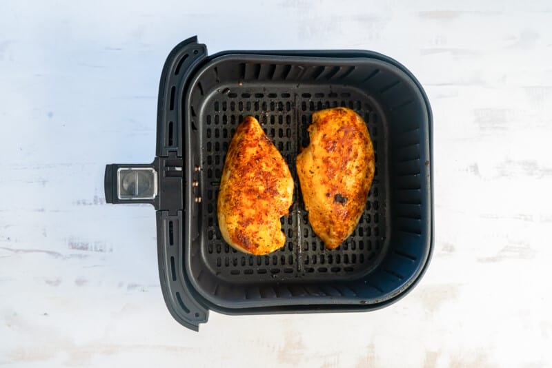 2 chicken breasts in air fryer basket after cooking