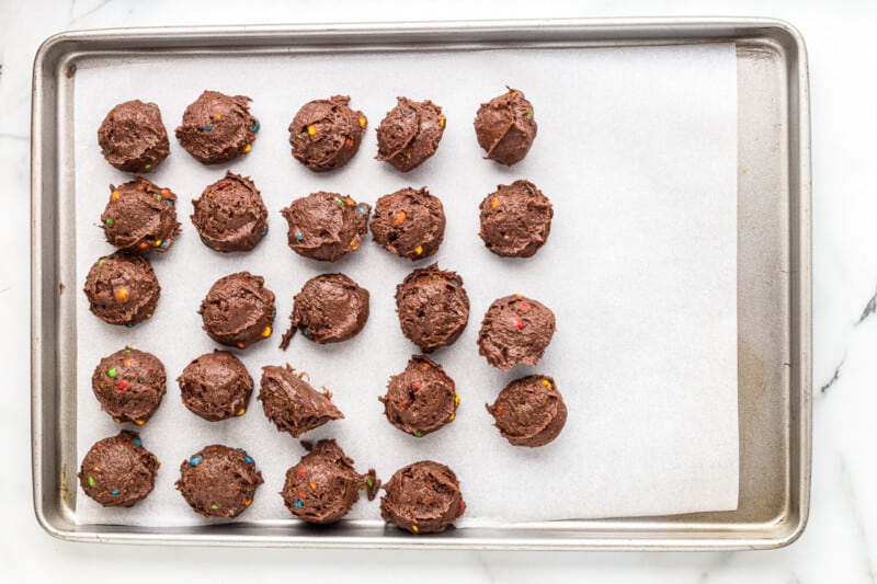 scooped cookie dough on a parchment paper lined baking sheet