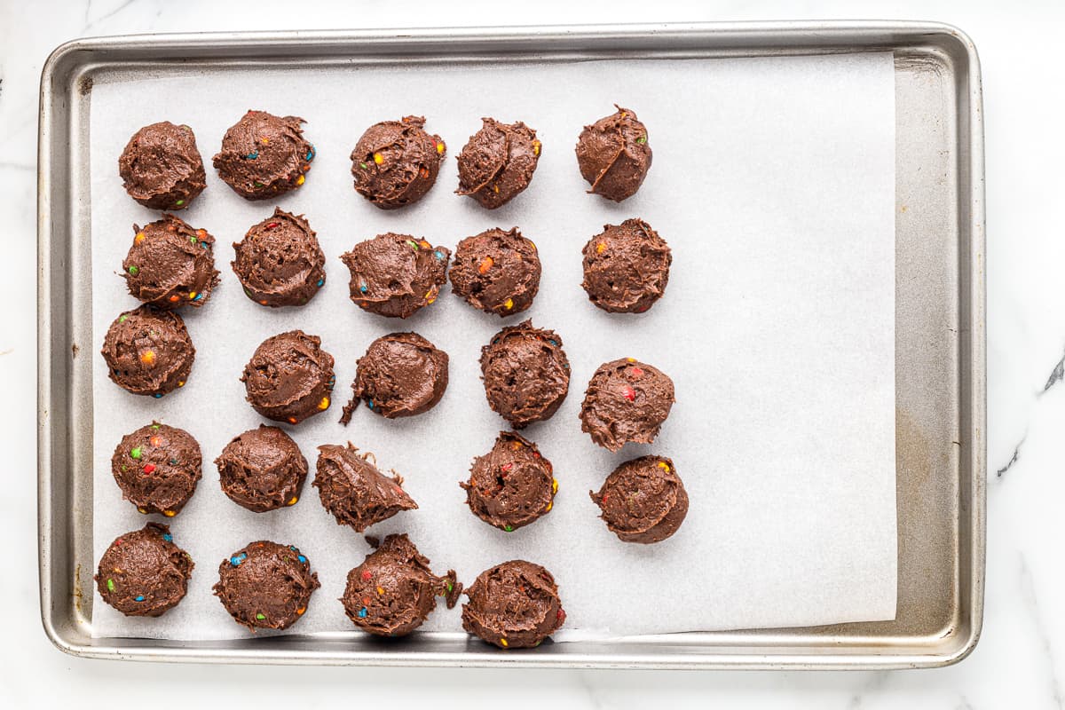 scooped cookie dough on a parchment paper lined baking sheet.