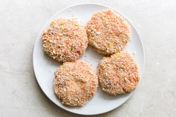 salmon burger patties with breadcrumb coating on a white plate