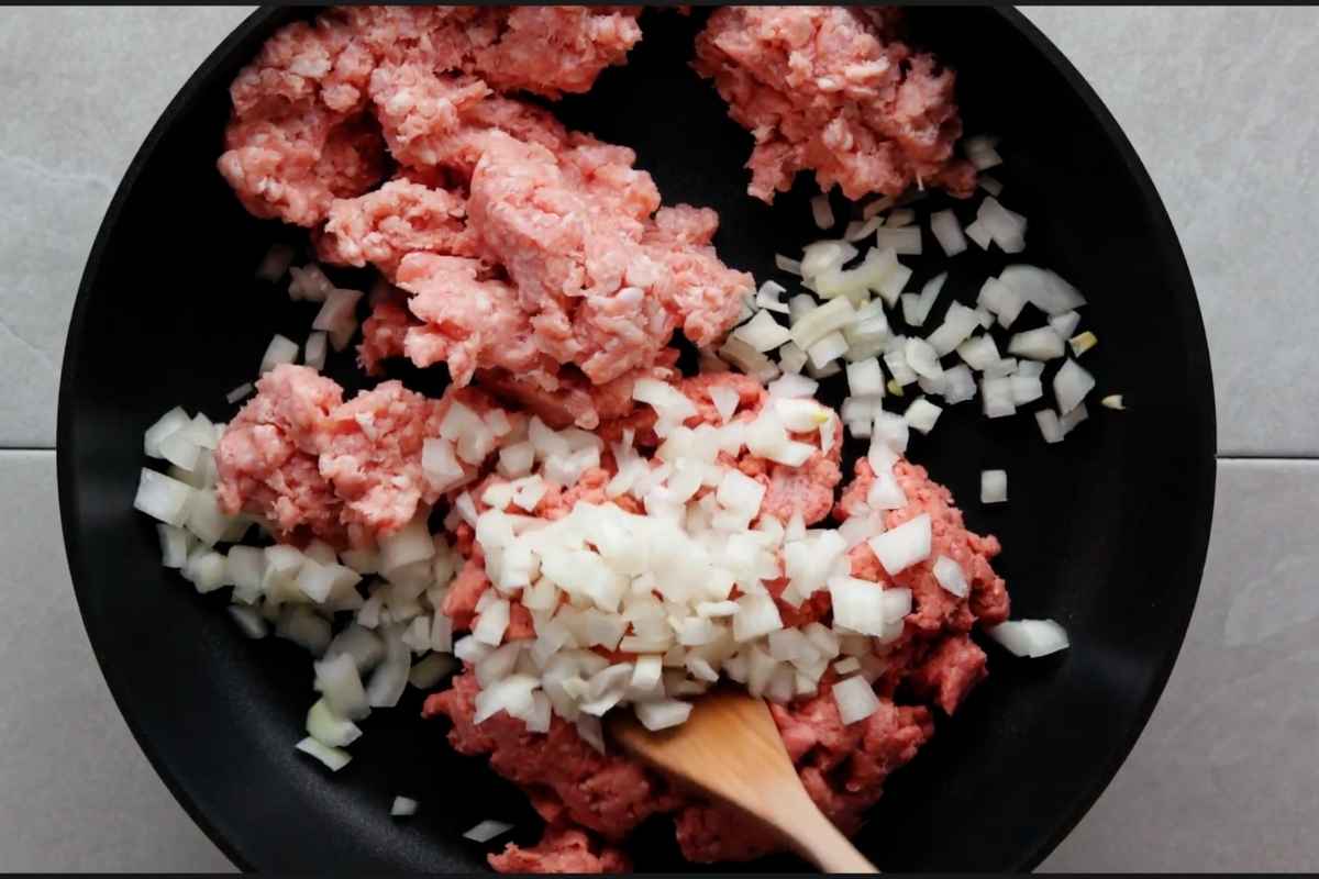 Adding ground chuck, pork and chopped onion on a large skillet on medium-high heat. Stir.