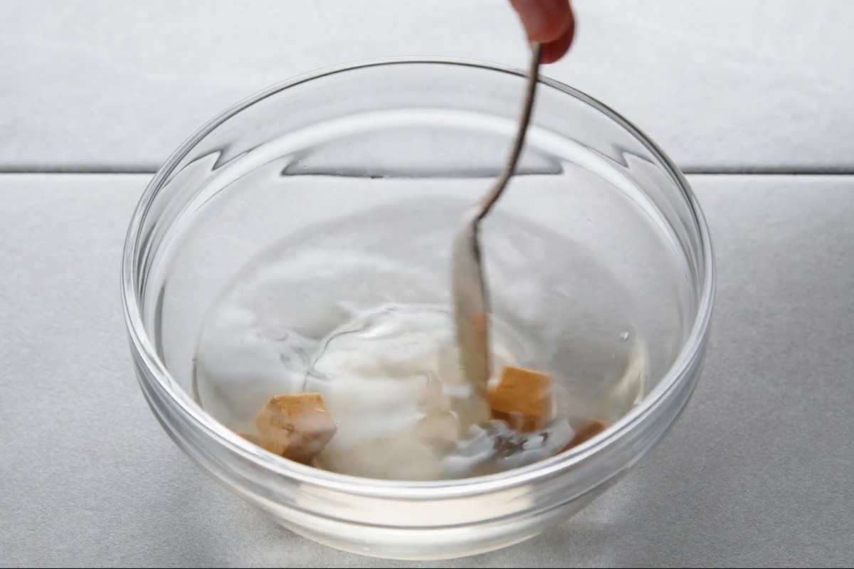 Dissolving bouillon cubes with water in a glass bowl. Stir with spoon.