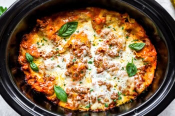 lasagna in a crockpot topped with fresh basil.