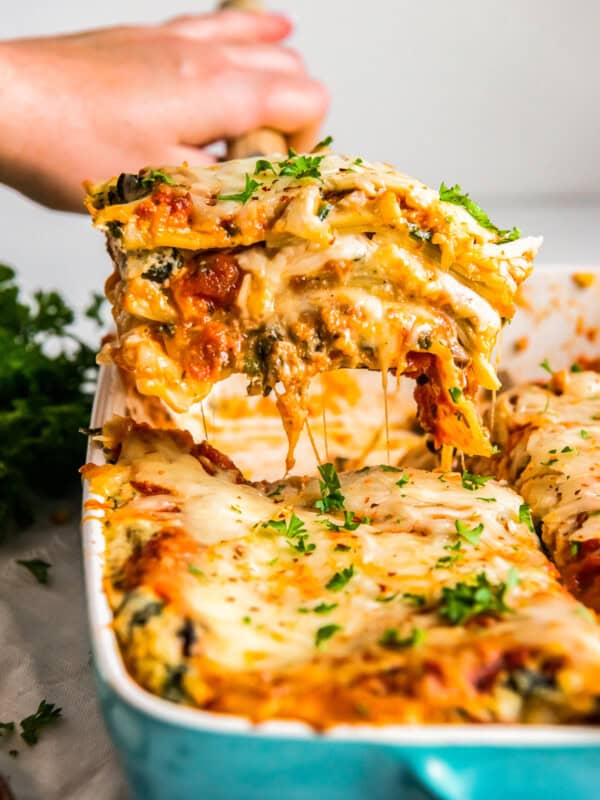 hand removing a slice of vegetarian lasagna from the baking dish with a spatula