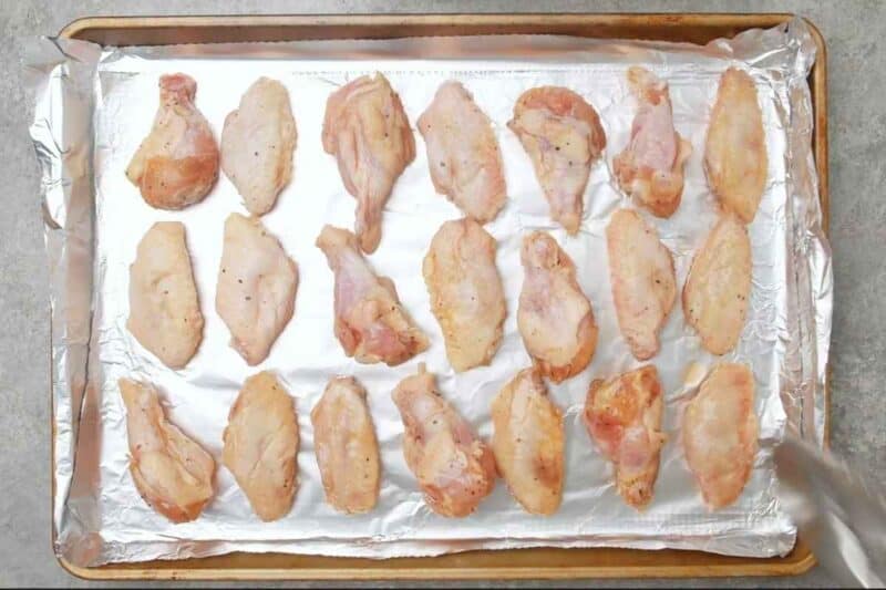 arranging marinated chicken wings on a prepared baking sheet.