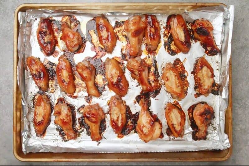 chicken wings arranged in a baking sheet after baking.