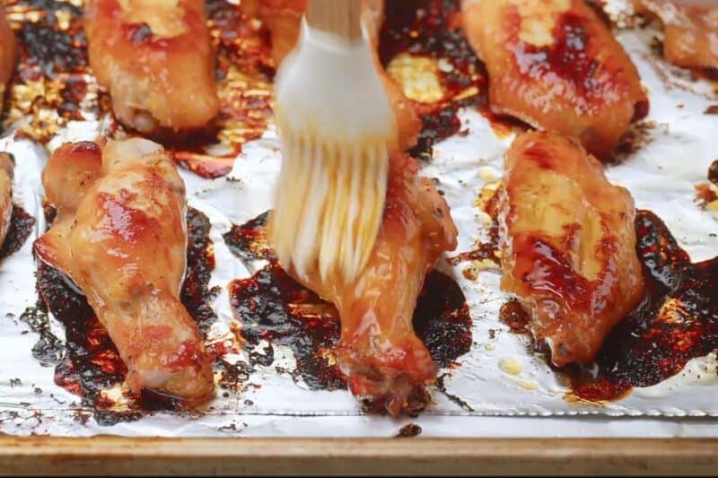 Liberally brushing glaze on baked chicken wings