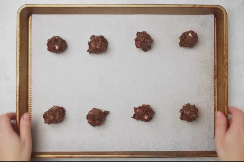 cookies dough balls lined on baking sheet.