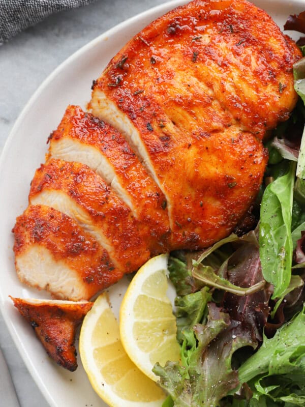 sliced chicken breast on a white plate with salad