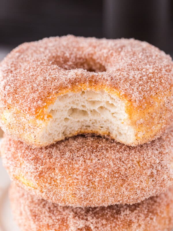 stack of 3 cinnamon sugar donuts with a bite taken from the top one