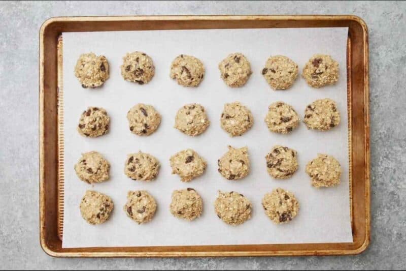 scooping out cookie dough on a lined baking sheet