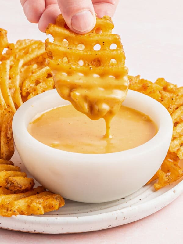 hand dipping a waffle fry into a bowl of chick-fil-a sauce