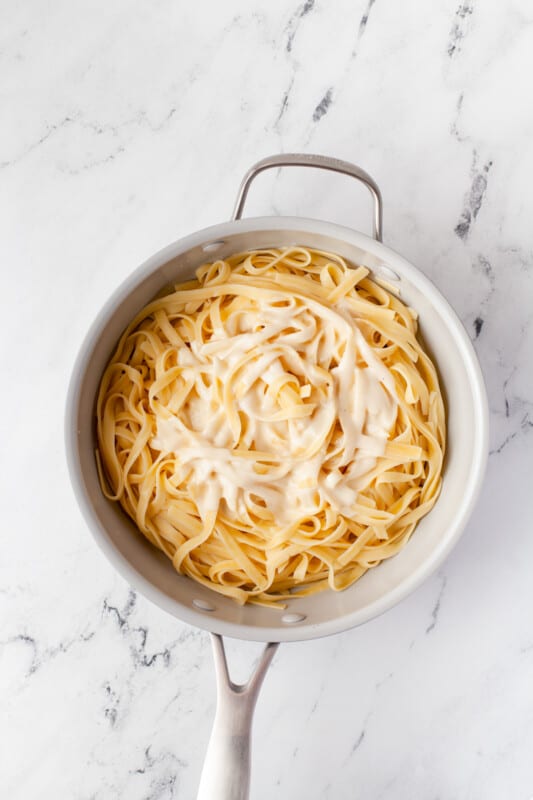 Alfredo sauce on top of fettuccine noodles in a saucepan