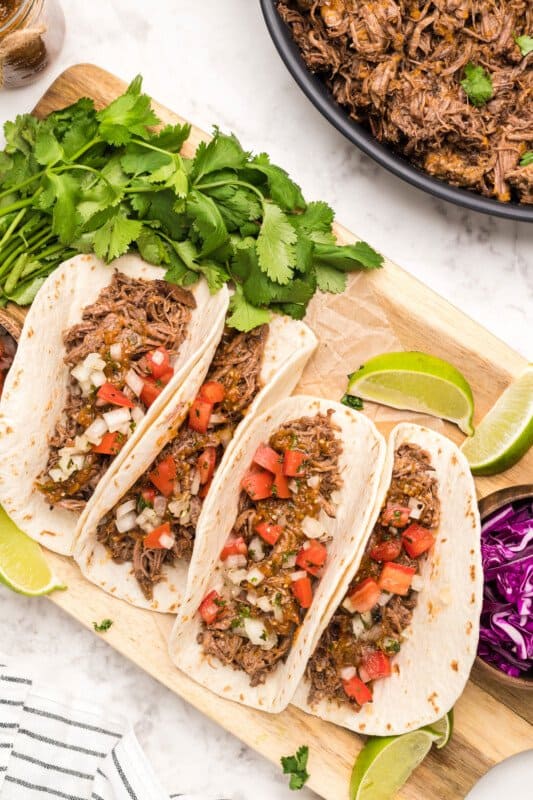 barbacoa tacos topped with pico de gallo and red tomatillo salsa