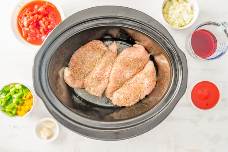 seasoned raw chicken breasts in a crockpot