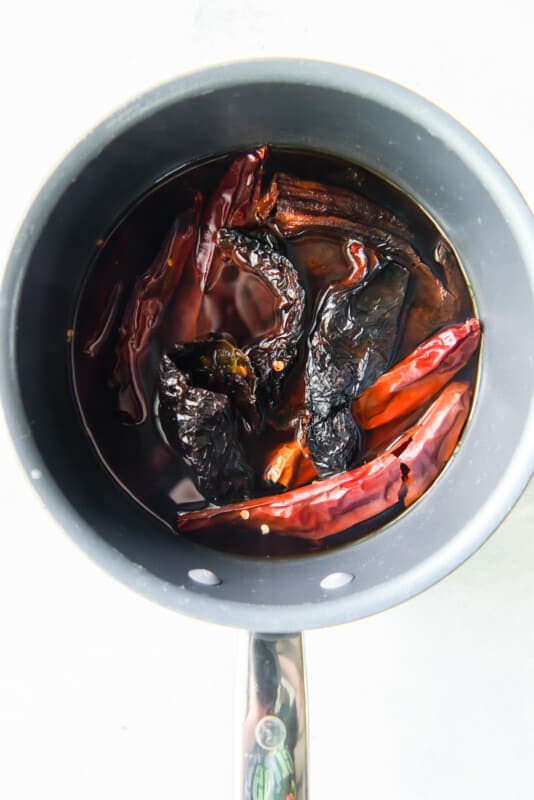 dried peppers soaking in a pot of hot water